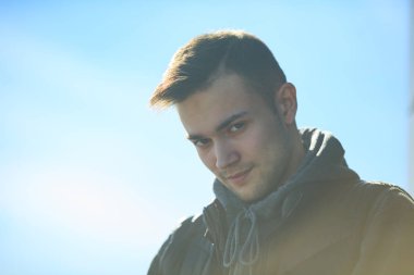 Sokağın karşısında bahar mavi gökyüzünde kapalı gözler ile mutlu bir genç yakışıklı erkek portresi.