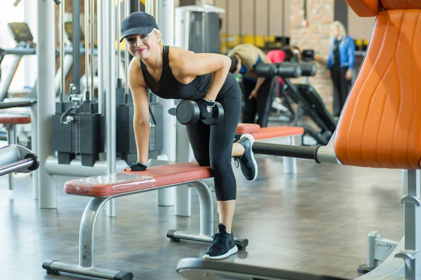Güzel sarışın Olgun kadın siyah eşofman takım elbise ve bir kap halter salonunda ile çalışmaları yapar. Spor eğitim.