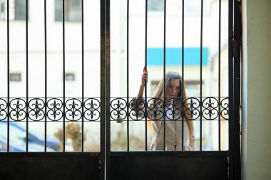 Vape genç. Gündelik giyim genç güzel beyaz kız bahar sokakta Vintage metal kapıları yakın bir elektronik sigara sigara. Kötü alışkanlık. Vaping aktivitesi.