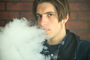 Vape genç. Barda elektronik sigara içen genç yakışıklı adamın portresi. Sağlık için zararlı kötü alışkanlık. Vaping etkinliği.