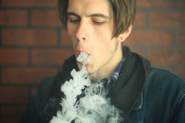Vape genç. Barda elektronik sigara içen genç yakışıklı adamın portresi. Sağlık için zararlı kötü alışkanlık. Vaping etkinliği.