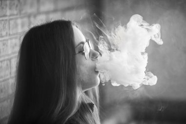 Sorunlu cildi olan Vape genç. Barda elektronik sigara içen güneş gözlüğü genç sevimli kız Portresi. Sağlık için zararlı kötü alışkanlık. Vaping aktivitesi. Siyah nad beyaz.