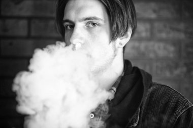 Vape genç. Barda elektronik sigara içen genç yakışıklı adamın portresi. Sağlık için zararlı kötü alışkanlık. Vaping aktivitesi. Siyah nad beyaz.