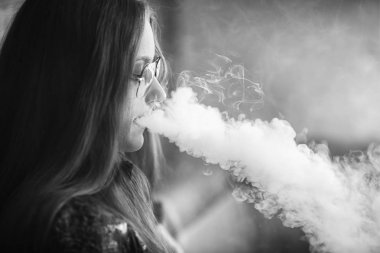 Sorunlu cildi olan Vape genç. Barda elektronik sigara içen güneş gözlüğü genç sevimli kız Portresi. Sağlık için zararlı kötü alışkanlık. Vaping aktivitesi. Siyah nad beyaz. Yakın çekim.