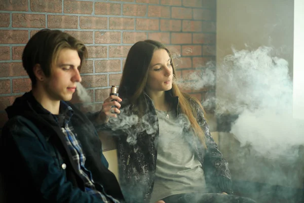 Vape gençleri. Güneş gözlüğü genç sevimli kız ve genç yakışıklı adam vape barda bir elektronik sigara duman. Sağlık için zararlı kötü alışkanlık. Vaping etkinliği.