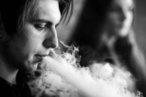 Vape gençleri. Güneş gözlüğü genç sevimli kız ve genç yakışıklı adam vape barda bir elektronik sigara duman. Sağlık için zararlı kötü alışkanlık. Vaping aktivitesi. Siyah beyaz.