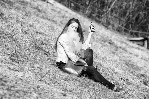 流浪少年在春天的一个阳光明媚的日子里 穿着休闲服装的年轻漂亮的白人女孩在山坡上抽烟 坏习惯血管活动 — 图库照片