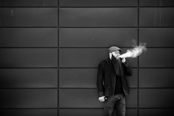 Vape 모자와 선글라스에 수염을 남자는 담배를 피우고 화창한 전화로 이야기합니다 — 스톡 사진