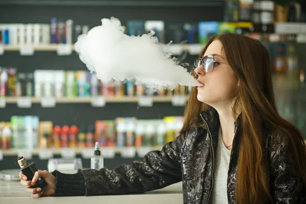 Vape genç. Güneş gözlüğü genç sevimli kız portresi vape barda elektronik sigara içen. Sağlık için zararlı kötü alışkanlık. Vaping etkinliği.
