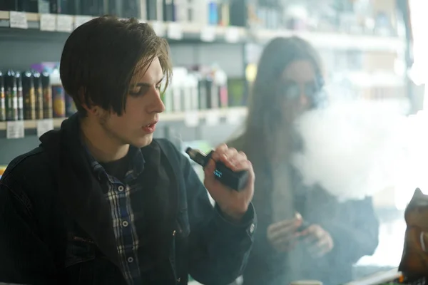 Vape gençleri. Genç yakışıklı adam ve güneş gözlüğü genç sevimli kız vape barda elektronik sigara duman. Sağlık için zararlı kötü alışkanlık. Vaping etkinliği.