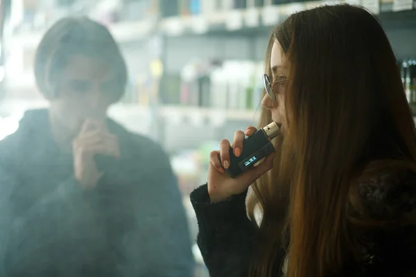 Vape gençleri. Güneş gözlüğü genç sevimli kız ve genç yakışıklı adam vape barda bir elektronik sigara duman. Sağlık için zararlı kötü alışkanlık. Vaping etkinliği.