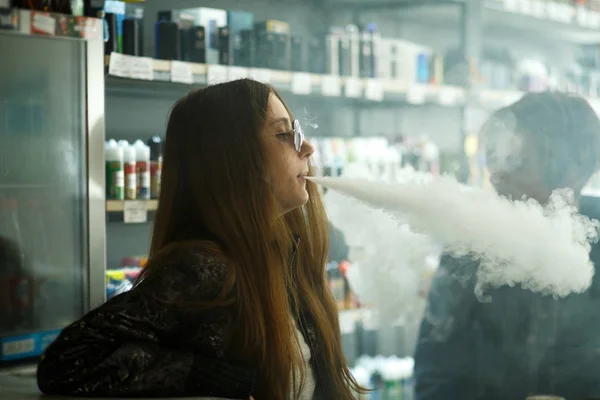 Vape gençleri. Güneş gözlüğü genç sevimli kız ve genç yakışıklı adam vape barda bir elektronik sigara duman. Sağlık için zararlı kötü alışkanlık. Vaping etkinliği.