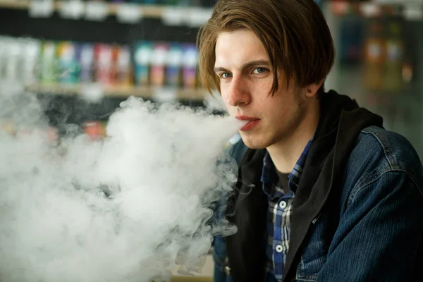 Vape genç. Vape barda elektronik sigara içen genç yakışıklı adamın portresi. Sağlık için zararlı kötü alışkanlık. Vaping etkinliği.