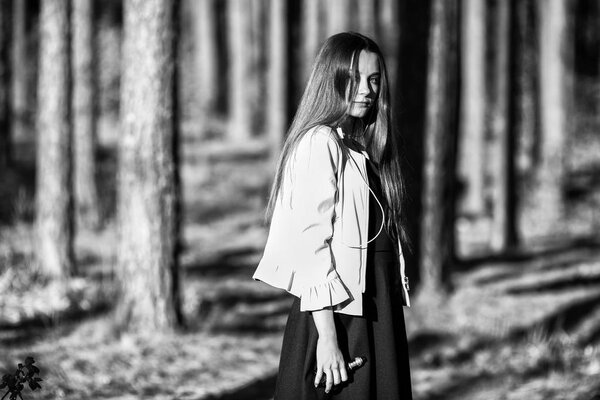 Vape teenager. Young cute girl in casual clothes smokes an electronic cigarette outdoors in the forest at sunset in summer. Bad habit that is harmful to health. Vaping activity. Black and white.
