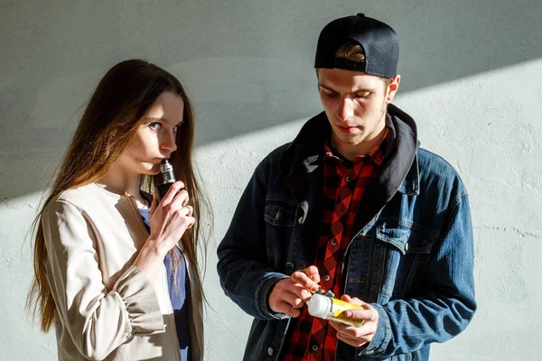 流浪少年年轻的可爱的女孩在休闲服装和帅哥在帽子吸烟电子香烟户外 有害健康的坏习惯 血管活动 — 图库照片