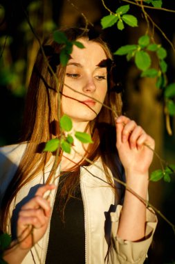 Bir yaz akşamı gün batımında ormanda rahat giysiler içinde uzun saçlı genç bir güzel beyaz genç kız portresi.