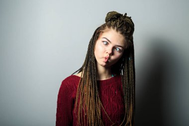 Afrika örgü ve problem cilt ile komik duygusal genç güzel beyaz genç kız shot yakın ve silah ile Maroon kazak göğüs üzerinde geçti.