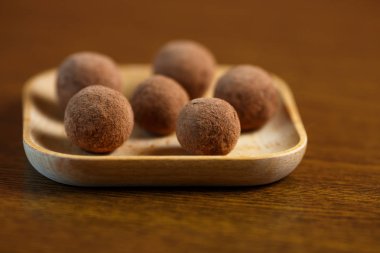 Masanın üzerinde tahta bir tabak üzerinde kurutulmuş meyve ve kakao tozu topları şeklinde ev yapımı şeker. Şeker ve gluten olmadan sağlıklı gıda.