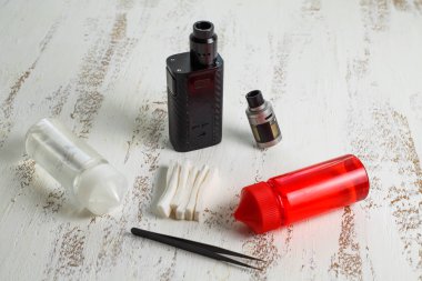Vape nesneleri. Hafif ahşap bir masa üzerinde e-sıvı ile elektronik sigara ve kavanoz.