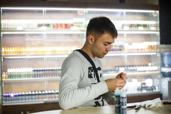 Vape man. Indoor portrait of a young handsome white caucasian guy in vape bar. Bad habit. Close up.