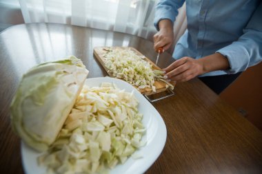 Kadın eller mutfakta masada tahta bir plaka üzerinde lahana kesti. Uygun beslenme.