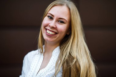 İlkbaharda sokakta kahverengi arka plan karşısında beyaz gömlek sorunlu deri ile genç bir sevimli kafkas kız Portresi.