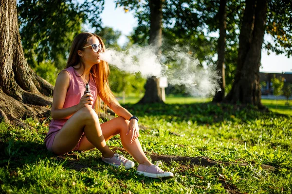 Vape tiener. Jonge mooie sportieve Kaukasische meisje in een roze sprong — Stockfoto