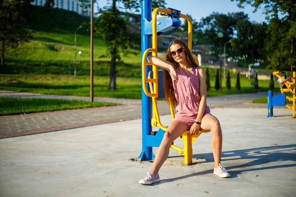 夏の晴れた日に公園のストリートスポーツフィールドでピンクのジャンプスーツとサングラスを着た若いかわいいスポーティな白人の女の子 ストリートスポーツグラウンドでのフィットネス — ストック写真