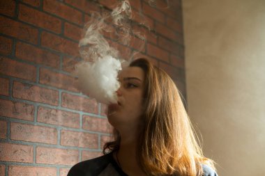 Sorunlu cildi olan Vape genç. Barda elektronik sigara içen genç sevimli kız portresi. Sağlık için zararlı kötü alışkanlık. Vaping etkinliği.