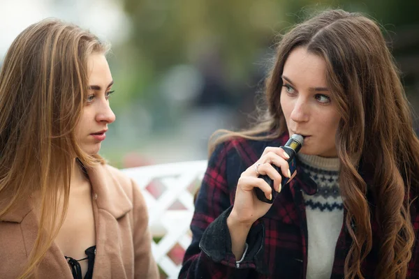 옷차림을 아름다운 소녀들 저녁에 거리에서 빈티지 벤치에 담배와 담배를 피웁니다 — 스톡 사진