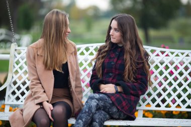 Biseksüel ilişki genç beyaz kızlar sonbaharda sokaktaki bankta. Lezbiyen çift aşk hikayesi. Lgbt topluluğu.