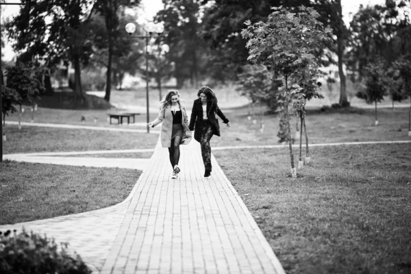 Bisexual relationship lesbian young caucasian teenage girls on the street in the autumn. Lesbian couple love story. LGBT community. Black and white.