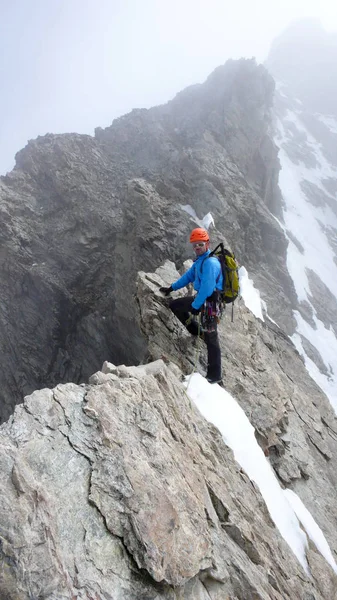 male mountain guide lead climbing on an exposed granite ridge in the Alps