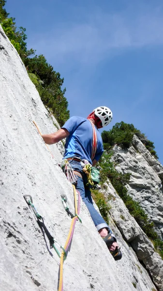 mountain guide climbing a steep slab pitch of a hard rock climbing route in the Alps of Switzerland
