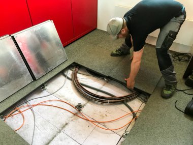 Genç erkek elektrikçi kablo döşemenin içinde çalışan ve zemin panelleri erişim kaldırma