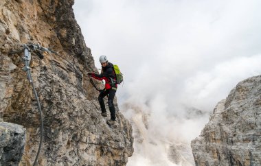 Alta Badia South Tyrol içinde bir Via Ferrata genç çekici kadın üniversite öğrencisi bir dik ve maruz rock yüzündeki tırmanıyor
