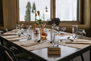 Restoran tablo zarif yer ayarlarını ve çiçekler ve Fransızca olarak yazılmış bir ayrılmış işareti