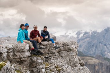 bir dağ tepe çıkıntı Dolomites içinde oturan ve muhteşem manzaraya bakarak dört genç erkek ve dişi yürüyüşçü