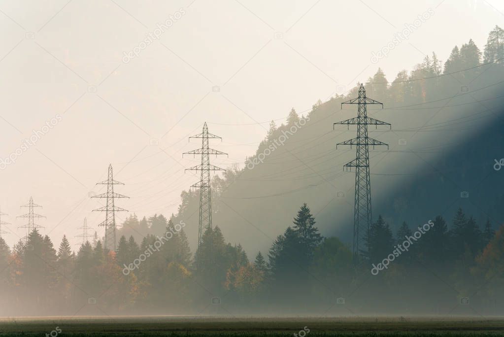 power lines and lattice crosses on a hazy morning in a mountain valley with fall color forest all around