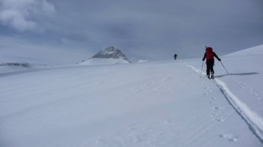 iki backcountry kayakçılar bir tırmanmaya uzak dağ tepe doğru yola yeni parça koyarak Avusturya Alpleri'nde