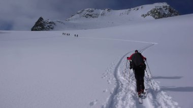 bir grup backcountry kayakçı zammı ve uzak dağ tepe İsviçre tırmanmaya