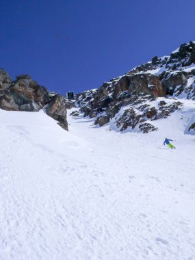 renkli kıyafet skiiing çok dik kar verdi derin kışın İsviçre Alpleri'nde teleferik istasyonunun altındaki aşağı erkekte