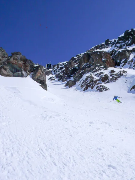 Человек Разноцветном Снаряжении Спускается Лыжах Крутому Снежному Кулуару Канатной Дорогой — стоковое фото