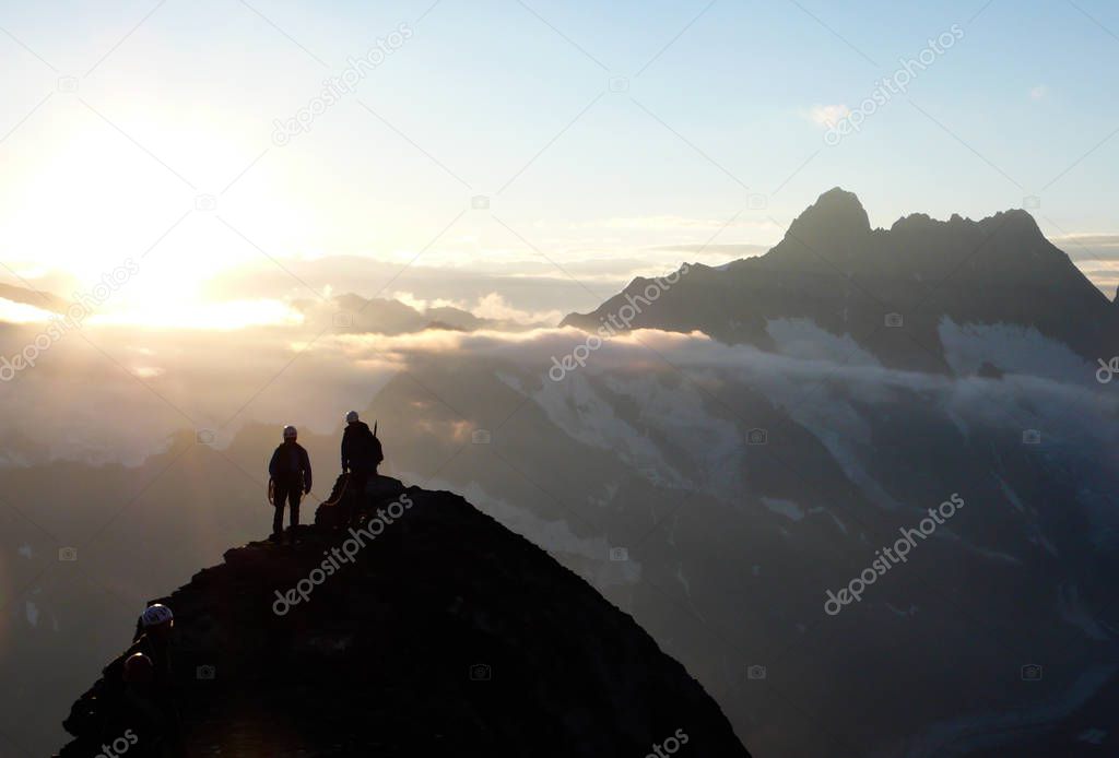 mountain climbers on a rocky ridge at sunrise climbing Eiger mountain in the Swiss Alps