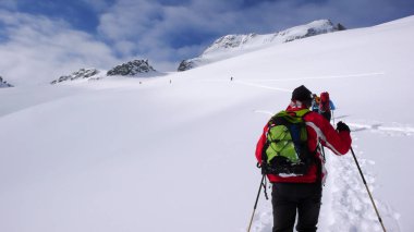 birkaç backcountry kayakçı zammı ve tırmanmaya uzak dağ tepe İsviçre bir güzel kış gününde