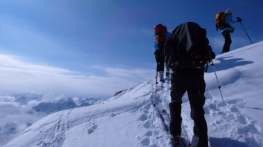 birkaç backcountry kayakçı zammı ve tırmanmaya uzak dağ tepe İsviçre bir güzel kış gününde