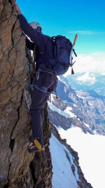 yüzünde bir maruz kalan ve dikey rock ve kar yüksek alp dağ tepe giderken aşırı dağcı