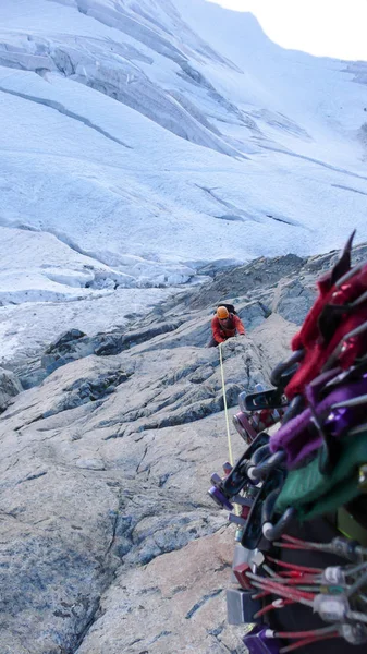 male mountain climber on an exposed climbing route high above a glacier