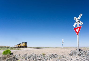 Alamogordo, Nm / Amerika Birleşik Devletleri - 10 Temmuz 2016: Union Pacific yük treni tarihinde karayolu 54 Alamogordo dışında bir demiryolu geçiş New Mexico çölünde haçlar