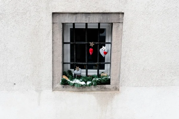 imaginative advent calendar and Christmas decorations hanging from a ground floor window in a snowy village in the Swiss Alps